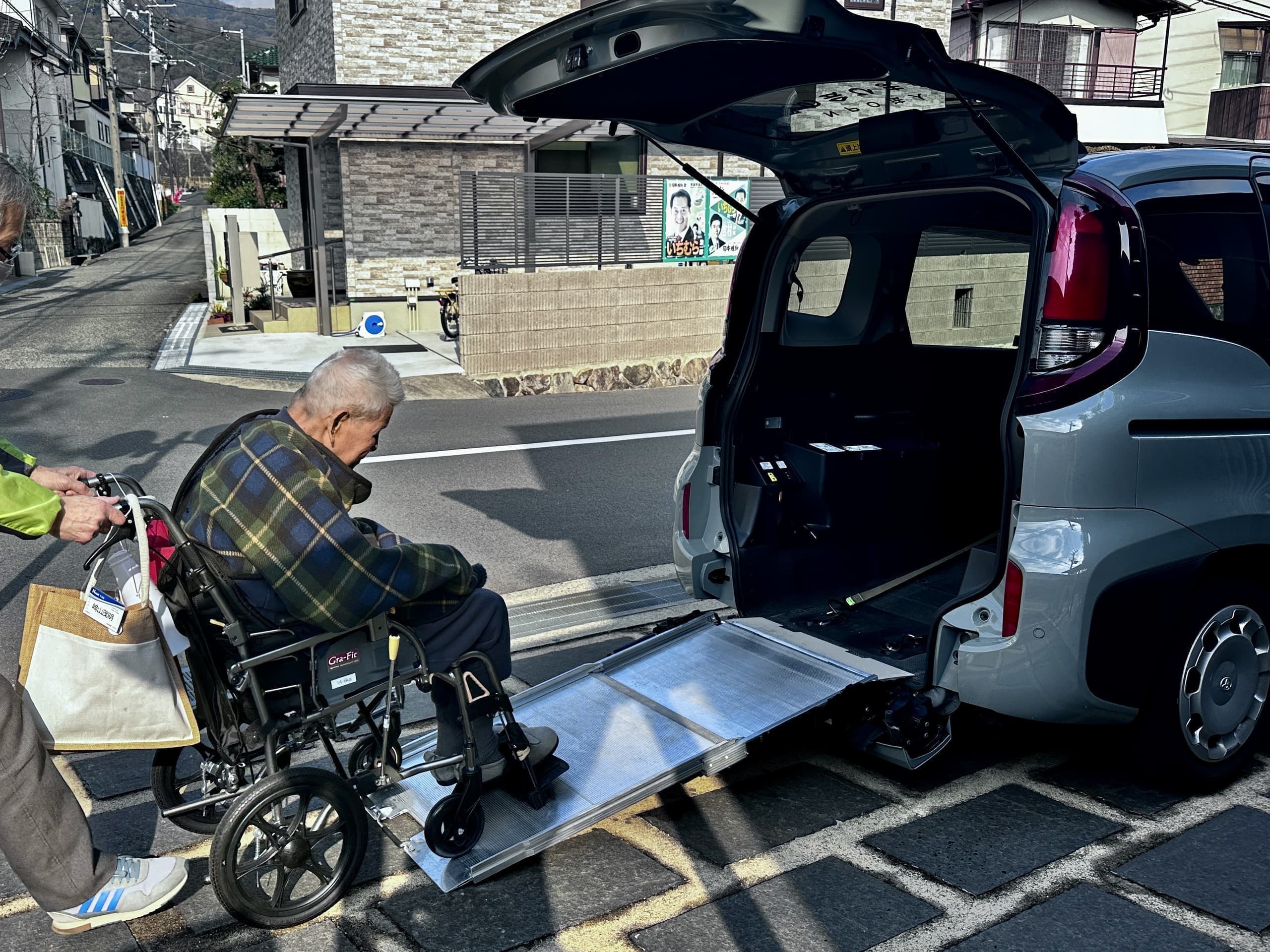 介護車両への乗降支援。車椅子利用者が専用スロープから福祉車両に乗り込む様子